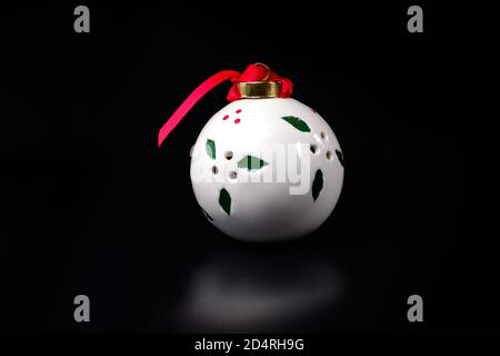 Weiße Kugel mit rotem Band auf schwarz. Neujahrsbaumschmuck Stockfoto