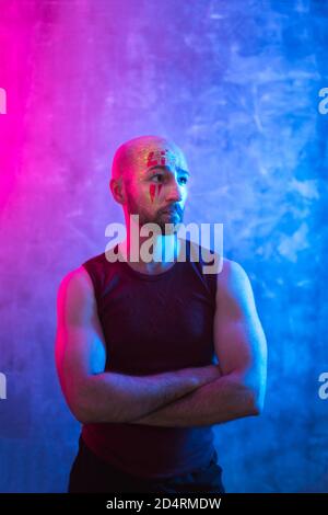 Bemalter bärtiger Mann in fluoreszierendem Pulver. Farbenfrohe, ungewöhnliche Aufnahmen mit Platz für Kopien. Stockfoto