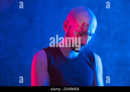 Porträt von stilvollen Glatze Mann mit Zeichnung auf Gesicht. Fluoreszierende Farbe in ultraviolettem und neonem Licht, kopieren Raum. Stockfoto