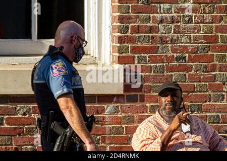 Ellicott City, MD, USA 10/07/2020: Ein weißer Polizist mit rasierten Kopf, der kurze und T-Shirt-artige Uniform und Gesichtsmaske trägt, spricht mit Stockfoto
