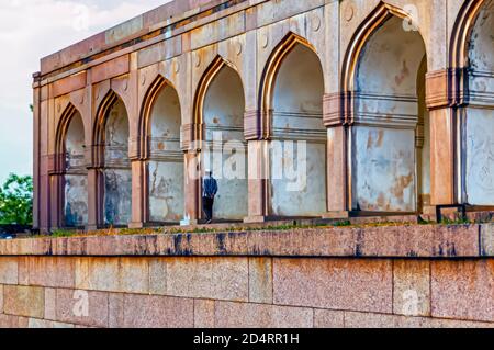 Ein Mann steht unter den Bögen/Torbögen im Inneren der Qutb Shahi Gräber in Ibrahim Bagh in Hyderabad, Indien. Stockfoto