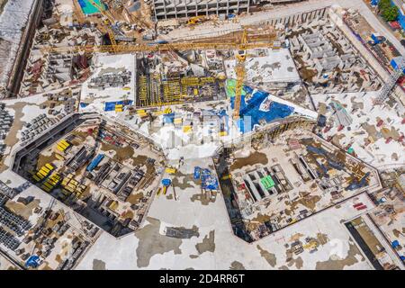 Aerial Draufsicht auf Gebäude mehrstufigen Fundament in der Stadt Baustelle. Hohe Turmdrehkrane und schwere Maschinen arbeiten Stockfoto