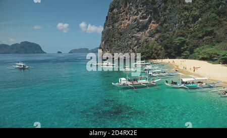 Philippinen Bootstour Luftaufnahme. Touristen auf Passagierschiffen an der Sandküste. Lokale Bootstour auf der Palawan Insel für Reisende. Epische tropische Asien-Seesicht der Dschungelgebirgsinsel in Filmaufnahme Stockfoto