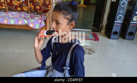 02. Oktober 2020 : Reengus, Jaipur, Indien / kleine Mädchen kauen auf grundlegende Telefon vintage Ton Stockfoto