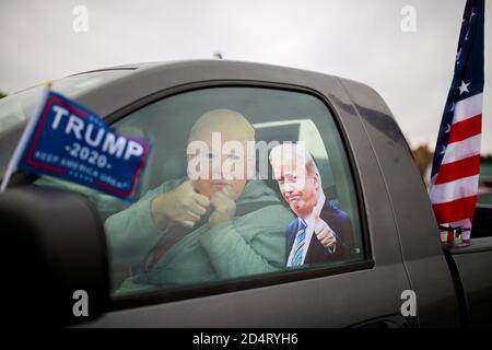 Martinsville, Usa. Oktober 2020. Ein Trump-Anhänger mit einer Maske posiert in seinem Auto und gibt Daumen nach oben Geste. Trump-Anhänger versammeln sich auf einem Parkplatz, bevor sie an einer Donald J. Trump Parade am Samstag teilnehmen. Trump kämpft für eine zweite Amtszeit als Präsident der Vereinigten Staaten, während er gegen den Demokraten Joe Biden kandidet, aber die Parade wurde vor Ort organisiert. Die Wahl ist drei Wochen entfernt. Kredit: SOPA Images Limited/Alamy Live Nachrichten Stockfoto