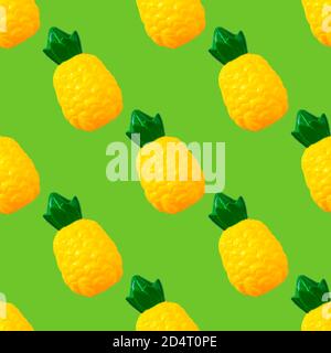 Ananas in nahtlosem Muster. Spielzeug Kunststoff Obst isoliert auf grünem Hintergrund. Plastikfrüchte für das Spiel. Spielen im Kindergeschäft Stockfoto