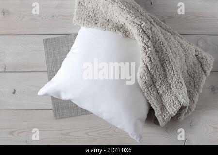 Weißes Kissen und weicher, flauschiger Teppich auf der Holzoberfläche. Stockfoto