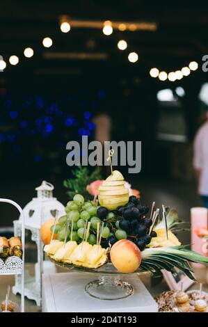 Verschiedene frische Früchte auf dem Hochzeitstisch. Tischdekoration für Hochzeiten. Obstbuffet am Empfang. Stockfoto