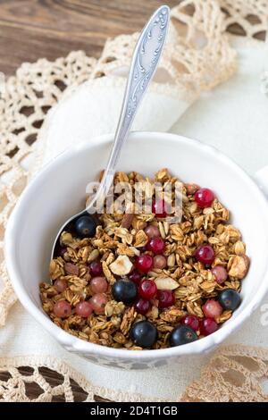 Hausgemachtes leckeres gesundes Müsli mit Nüssen, Samen, Honig und frischen Beeren in einem Keramikbecher Stockfoto