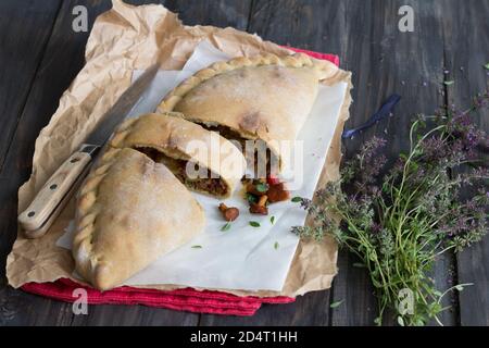 Italienische Pizza Calzone mit Pilzen, Spinat und Käse auf einer Holzoberfläche mit einem Bündel Thymian, rustikalen Stil, selektive Fokus Stockfoto