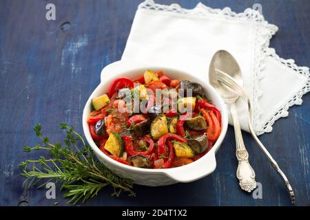 Ratatouille, ein traditionelles französisches Gericht aus frischem Gemüse in einer weißen Keramikschale auf dunkelblauem Hintergrund Stockfoto