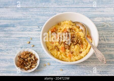 Maisbrei mit Kürbis, Honig und Walnüssen auf blauem Holzhintergrund Stockfoto