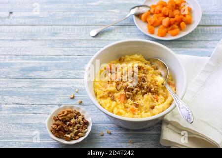 Maisbrei mit Kürbis, Honig und Walnüssen auf blauem Holzhintergrund Stockfoto