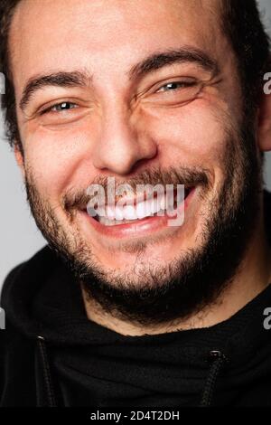 Fröhlicher schöner Mann, Freude und Hoffnung. Ein junger Mann mit lächelndem Bart. Schönes Lächeln, blaue Augen. Zufriedenheit und Erfolgskonzept. Stockfoto