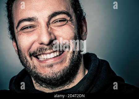 Freude und Glück, fröhlich und glücklich. Ein junger Mann mit lächelndem Bart. Schönes Lächeln, blaue Augen. Zufriedenheit und Erfolgskonzept. Stockfoto