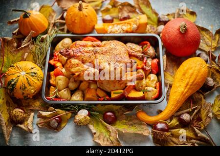 Gebratenes Hähnchen oder pute garniert mit Kürbissen, Pfeffer und Kartoffeln. Serviert auf einem rustikalen Tisch mit Herbstgemüse, Kastanien und dekoriert Stockfoto
