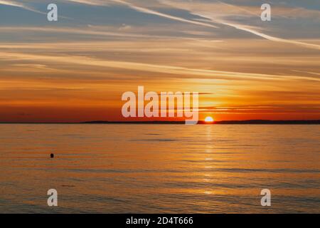 Die Sonne geht über den walisischen Hügeln unter Ein ruhiger Abend am Clevedon Beach und Beleuchtung der Horizont mit Multicoloren Stockfoto