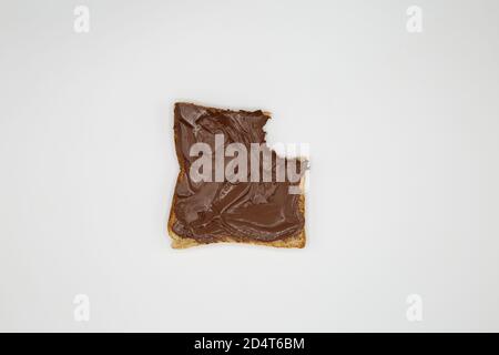 Ansicht von oben nach unten auf einzelne gebissene Scheiben Toastbrot mit Glänzend braune Nuss Nougat Creme auf weißem blanken Hintergrund verteilt Stockfoto