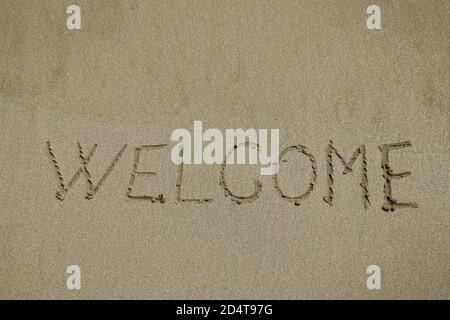 Inschrift willkommen auf einem nassen Sand. Willkommen, Textur auf dem Strand Sand Stockfoto