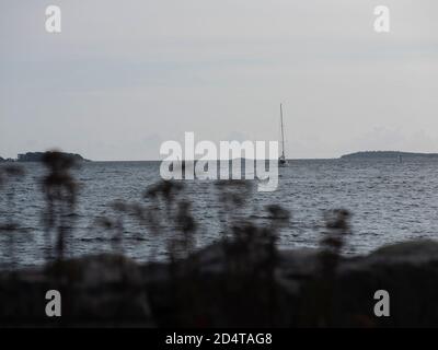 Helsinki/Finnland - 10. OKTOBER 2020: Die Silhouette eines kleinen Segelbootes, das an einem sonnigen Tag den Horizont überquert. Stockfoto