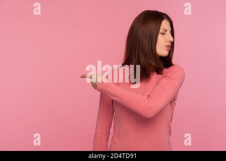 Wütend verärgert Frau in rosa Pullover zeigen Finger fragen raus, strenge Dame Chef Entlassung Mitarbeiter. Innenaufnahme des Studios isoliert auf rosa Hintergrund Stockfoto
