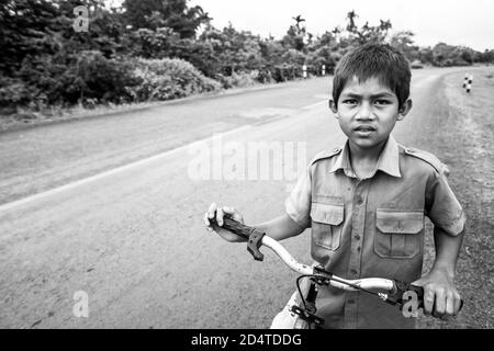 Pakse, Laos - 27. Oktober 2010: Laotischer Junge in Schuluniform mit Fahrrad auf der Nationalstraße T 16 von Salavan nach Pakse, Laos. Stockfoto