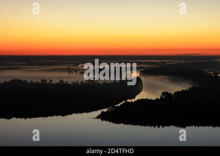 Wunderbare geisterhaft neblige Morgendämmerung über Silhouette der Insel und nebligen Fluss. Erstaunliche szenische warmen Sonnenaufgang mit Baum Silhouetten in Dunst. Atmosphärisch früh Stockfoto