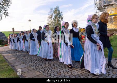 Crostwitz, Deutschland. Oktober 2020. Geistliche, Konfirmanden und ihre Paten gehen nach dem Konfirmationsgottesdienst um das Kirchgelände. In der Kirche Crostwitz erhalten etwa 40 Jugendliche ihre Konfirmation. Einige Frauen tragen traditionell das sorbische Kostüm. In der katholischen Kirche ist die Konfirmation eines der Sakramente nach der Taufe und Erstkommunion. Quelle: Matthias Rietschel/dpa-Zentralbild/ZB/dpa/Alamy Live News Stockfoto