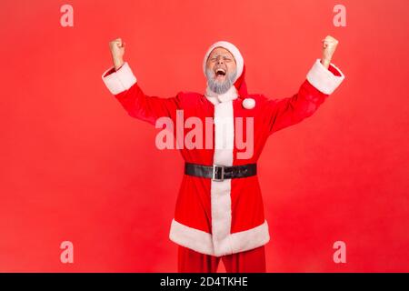 Portrait von extrem glücklich zufrieden santa claus steigt Hände auf und schreiend feiert seinen Sieg im Urlaub Lotterie, aufrichtige Emotionen. Innen s Stockfoto