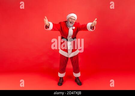 In voller Länge Porträt von lächelnden freundlichen Mann in santa claus Kostüm Heben Hände wollen umarmen und gratulieren, kostenlose Umarmungen, Magie der Feiertage. ICH Stockfoto