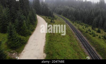 Die sandige Straße verläuft entlang der Eisenbahn. Stockfoto