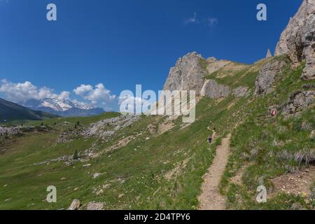 Nicht erkennbare Frau, die auf einem Wanderweg in einem wunderschönen Dolomitenszenario mit Marmolada-Gletscherhintergrund, Settsass, Dolomiten, Italien wandert Stockfoto