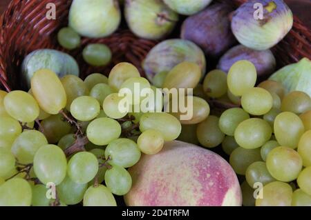 September violette Blüten und Früchte Feigen weißen Trauben in einem Korbkorb Stockfoto