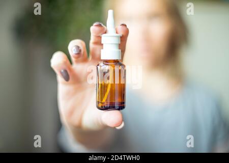 Nasenspray, weibliche Hand Sprühen Nasenspray mit verschwommenem Hintergrund. Medizin und Gesundheitswesen Konzept. Antivirenbehandlung. Stockfoto