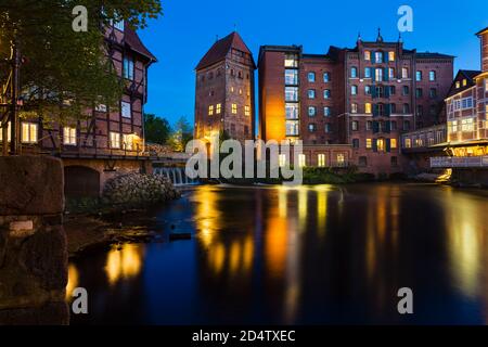 Alte Mühle und Hotel an der Ilmenau in der Lüneburger Altstadt mit nächtblauem Himmel. Stockfoto