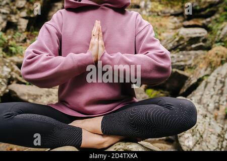 Ernte einer jungen Frau auf großen Stein mit gekreuzten Beinen sitzen Mit verbundenen Händen Stockfoto