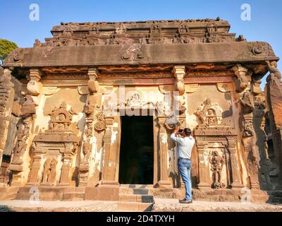 Tourist macht Fotos von Ellora Höhlen im Aurangabad Bezirk von Maharashtra, Indien, einer der größten Felsgestein Kloster-Tempel Höhlenkomplexe Stockfoto