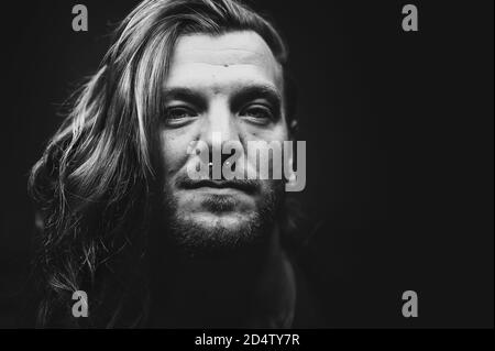 Mann mit langen Haaren schaut ernsthaft auf die Kamera Stockfoto