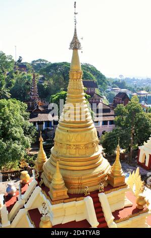 Blick auf eine goldene Pagode und religiöse Gebäude auf der Südseite der Kyaikthanlan Pagode oder die Old Moulmein Pagode in Mawlamyine, Myanmar Stockfoto