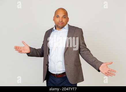 Junger afroamerikanischer Geschäftsmann, der die Kamera ansah, spreizte seine Hände schuldhaft. Ein unwissender und verwirrter Ausdruck mit erhobenen Armen und Händen. Zweifelskonzept Stockfoto