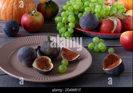Reife, frische Feigen, Trauben, Äpfel und Kürbisse auf einem Tisch mit Holzfläche. Ernte, Herbstfrüchte, gesunde Ernährung. Horizontale Ausrichtung, selektiv Stockfoto