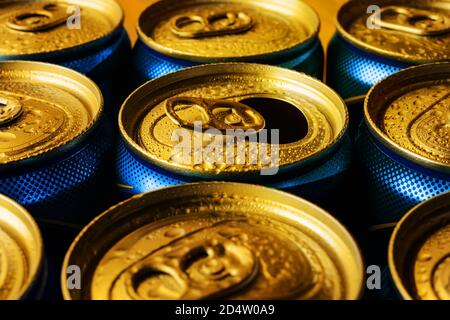 Goldene Bierkronen mit Wassertropfen. Volles und offenes kaltes Getränk in der Dose. Unterwegs Getränke in Dosen mit Zugtabs trinken. Nahaufnahme. Stockfoto