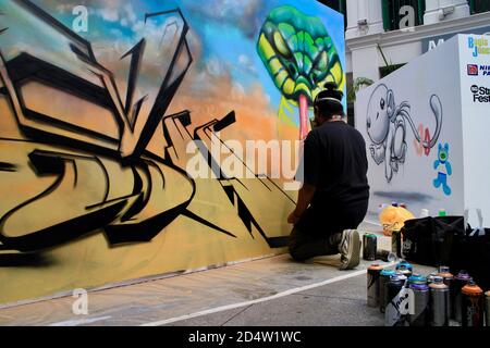 Männlich Singapurer Graffiti Künstler Spraying an der Wand zu machen Graffiti in der Bugis Street Stockfoto