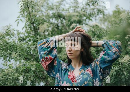 Porträt einer nachdenklichen Frau, die ihre Haare fixiert Stockfoto