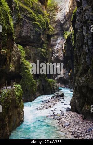 Das Sonnenlicht scheint in die dunkle Schlucht. Stürmisch, Bergfluss fließt durch die Schlucht. Stockfoto