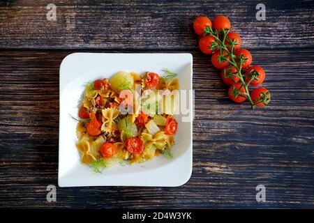 Deutsche Hausmannskost: Frischer Fenchel mit Hackfleisch, Pasta und Tomaten auf einem weißen Teller mit Holztisch Hintergrund. Stockfoto