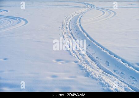 Schneemobil und Menschen hinterließen an einem Wintertag Fußspuren im Schnee. Stockfoto