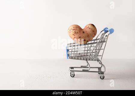Bio-Kartoffel in Form von Herz fliegen in Lebensmittelkarren auf weißem Hintergrund. Konzept Liebe hausgemachten hässlichen Gemüse. Stockfoto