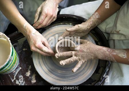 Hände arbeiten mit Ton auf einem Potter's Rad, Nahaufnahme. Teamarbeit in der Werkstatt Stockfoto