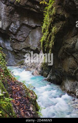 Wilder Gebirgsfluss mit klarem blauem Wasser fließt durch das offene Gebiet der Partnachklamm in Deutschland. Der schnelle Strom gleitet über die Felsen Stockfoto